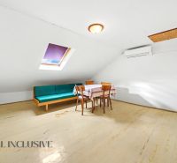 Interior of a family house with a sofa, table, chairs, and a window in the attic.