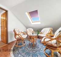 Attic room of a family house with four armchairs, a table, and a blue carpet.