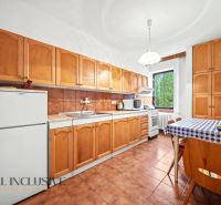Family house kitchen with wooden cabinets, refrigerator, and dining table.