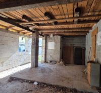 The interior of a family house with a wooden beam ceiling and an unfinished floor.