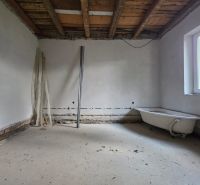 Interior of a family house under construction, with incomplete flooring and a bathtub.