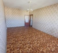 Wallpaper with a floral pattern and a floor with a wooden design in a studio apartment.