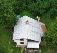 A cottage surrounded by trees in the Šugov Valley in Medzev with a grassy plot.
