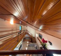 A cabin with a wooden ceiling and floor, view from the gallery to the living room.