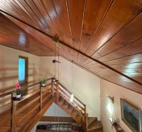 Wooden ceiling and staircase in the interior of the cabin with a floor featuring a wooden decor.