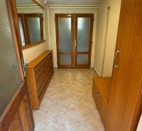 A hallway in a cabin with ceramic tiles, wooden furniture, and glass doors.