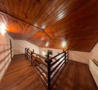 The attic of the cottage with a wooden decor floor and a wooden ceiling.