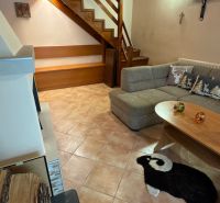 Interior of a cabin with a wooden staircase, a sofa, and a decorative sheep rug.