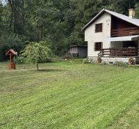 A cottage in the Šugov Valley near Medzev, surrounded by meadows and forests, with a wooden terrace.