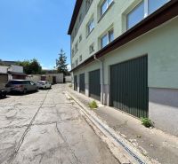 Parking lot in front of the offices in Kežmarok, next to the building with green garage doors.
