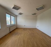 A spacious office with a wooden decor floor and large windows.