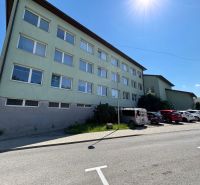 The exterior of offices in Kežmarok with parked cars on a sunny street.