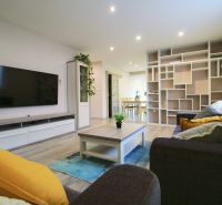 Living room in a family house with a wood-patterned floor and a large TV screen.