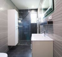A bathroom with a shower in a family house with gray-toned tiles.