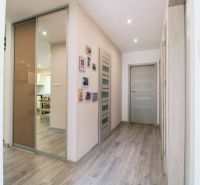 A hallway in a family house with a wooden decor floor and many doors.