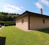 A family house in Bytča with a lawn, paving, and an access road, surrounded by greenery.