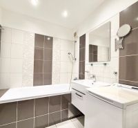 A bathroom in a 2-room apartment with a shower, sink, and washing machine, tiled.