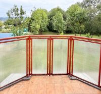 A balcony with a transparent railing and a view of greenery in a 2-room apartment on Mateja Bela in Žilina.