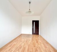 A room in a 2-room apartment with white walls and a wooden decor floor.