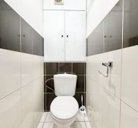 Bathroom with toilet in a 2-room apartment with light tiles and a towel rack.