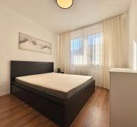 A bright bedroom with a bed, artwork on the wall, and a wooden decor floor in a 2-room apartment.