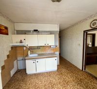 A kitchen in a 2-room apartment with a wooden decor floor and white cabinets.