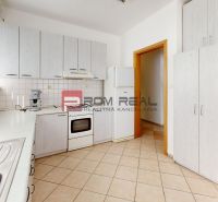 A kitchen area in a production facility with white cabinets, a sink, and a tiled floor.