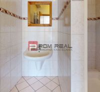 A bathroom in a production facility with a white sink and a mirror on the tiles.