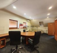 An office in a production area with a round table and black chairs.