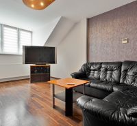 Living room with a black sofa set, television, and wooden decor flooring in a two-room apartment.