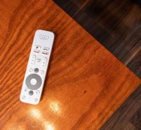 A remote control on a wooden table, next to a floor with wooden decor in a 2-room apartment.