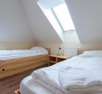 Attic room in a 2-room apartment with beds; floor with wooden decor.