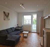 A comfortable living room with a sofa, a desk, and a wooden decor floor in a two-room apartment.