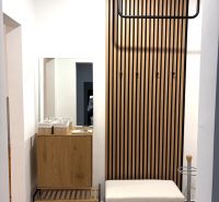 Hallway with a coat rack wall and a bench in a 3-room apartment with a wooden decor floor.