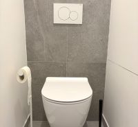 A minimalist bathroom with a tiled floor and a wall-mounted toilet in a 3-room apartment.