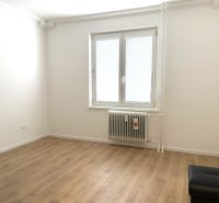 White room with a wood-patterned floor in a 3-room apartment with a radiator.