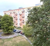 The exterior of an apartment building on Sklenárova Street in Bratislava-Nivy surrounded by greenery and cars.
