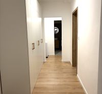 A hallway with a white wardrobe and a wooden decor floor in a 3-room apartment.