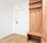 A kitchen unit in a 2-room apartment with a wooden decor floor and a dark countertop.
