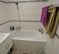 Bathroom with a white bathtub and sink in a 2-room apartment.