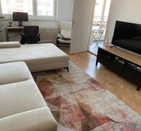 Living room with a sofa, desk, television, and wooden decor flooring.