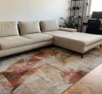 A light sofa and carpet in a 2-room apartment with a wooden decor floor.