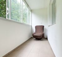 Enclosed balcony with a chair and tiles in a 3-room apartment.