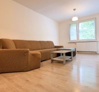 Living room with a sofa and wood-patterned flooring in a three-room apartment.