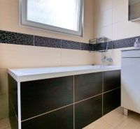 A bathroom with a shower, sink, and warm radiator in a 3-room apartment.