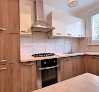 A kitchen in a 3-room apartment with wooden cabinets and a stove.