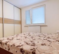 A bedroom in a 3-room apartment with a large wardrobe and a bed with floral bedding.