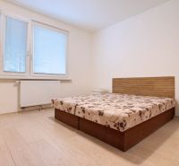 A bedroom in a 3-room apartment with a bed, a nightstand, and a floor with a wooden decor.