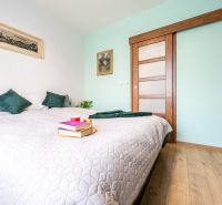 A bedroom in a two-room apartment with a wooden decor floor and simple decor.