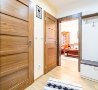 Interior of a 2-room apartment with a wooden decor floor, wardrobe, and coat rack.